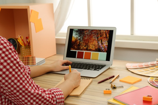 Female designer working at wooden table indoors, closeup