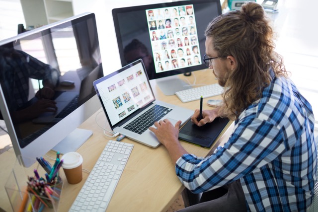 Male executive working over laptop and graphic tablet at his desk in office